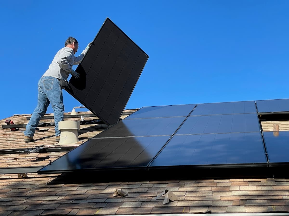 A technician installing a solar panel on a roof